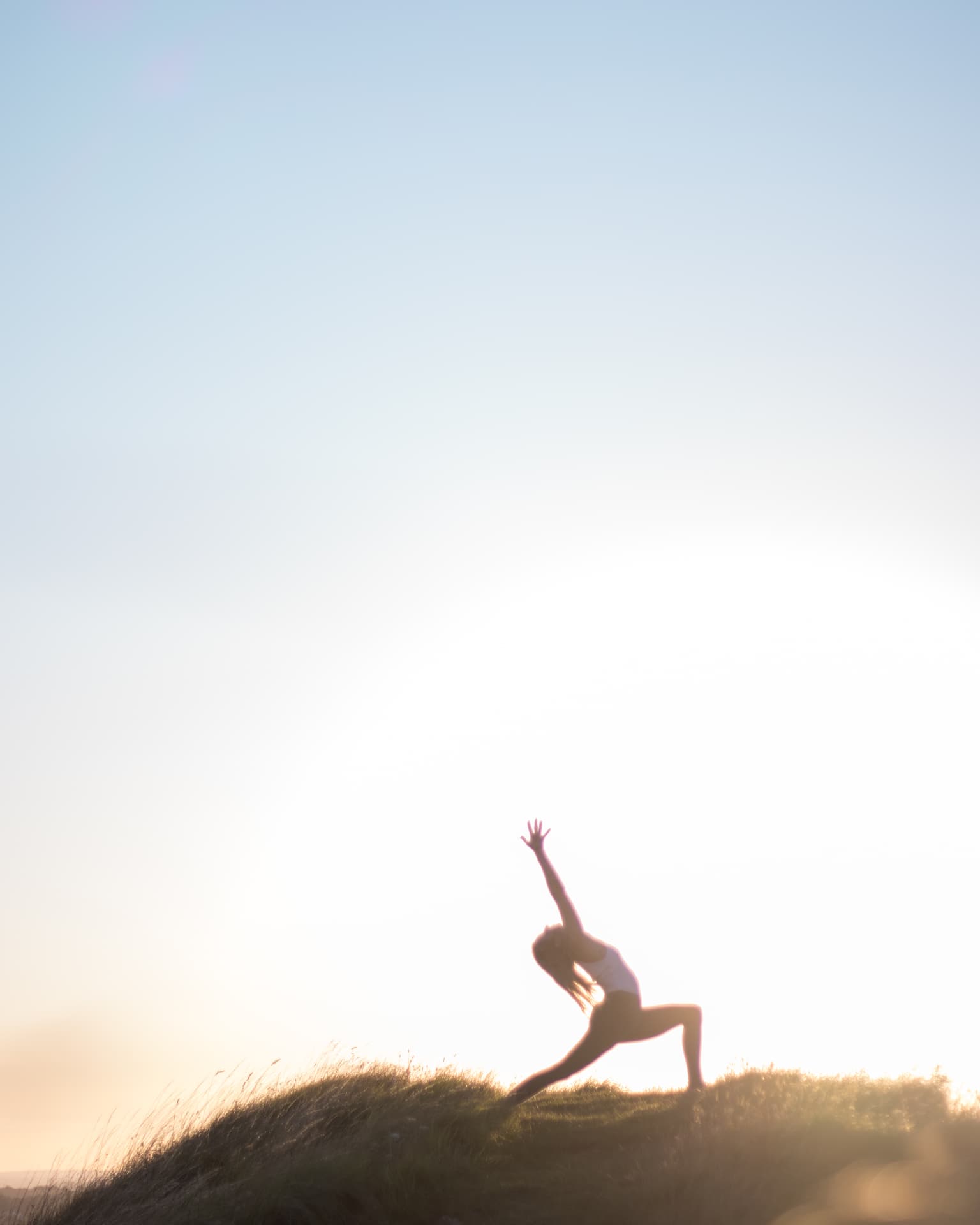 Silhouetted warrior pose against a sunrise sky